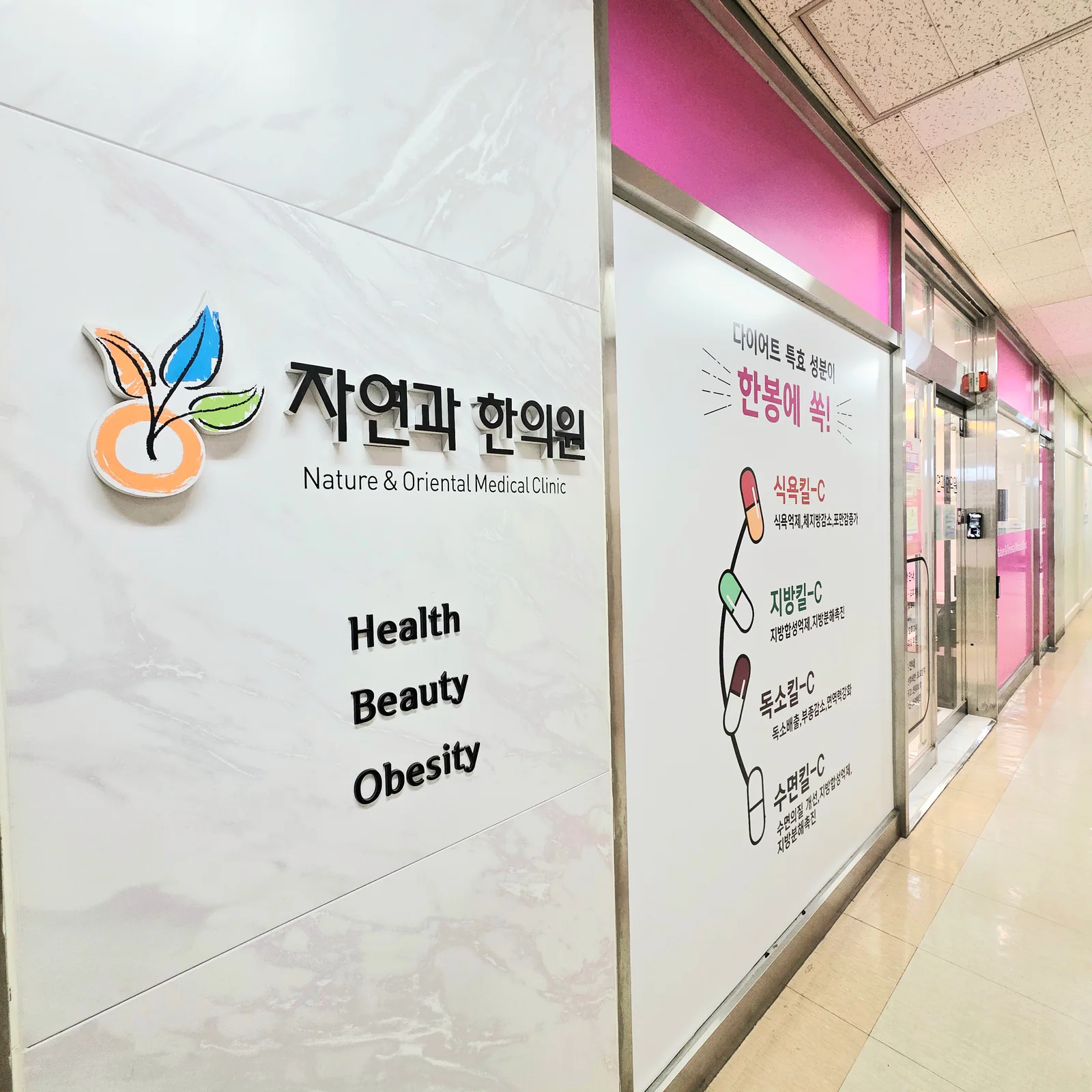 브라운스톤천호 3층 복도 벽의 자연과한의원 로고와 출입구