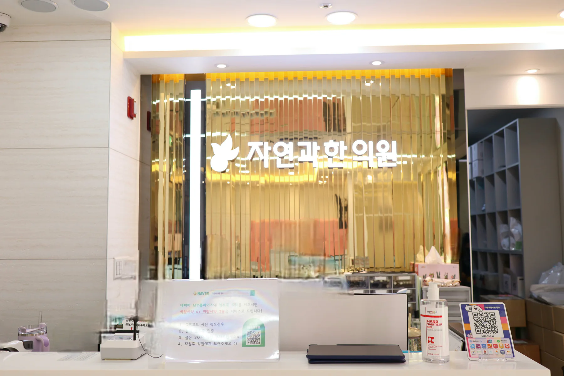 금빛 벽면 로고가 보이는 자연과한의원 천호점 접수처